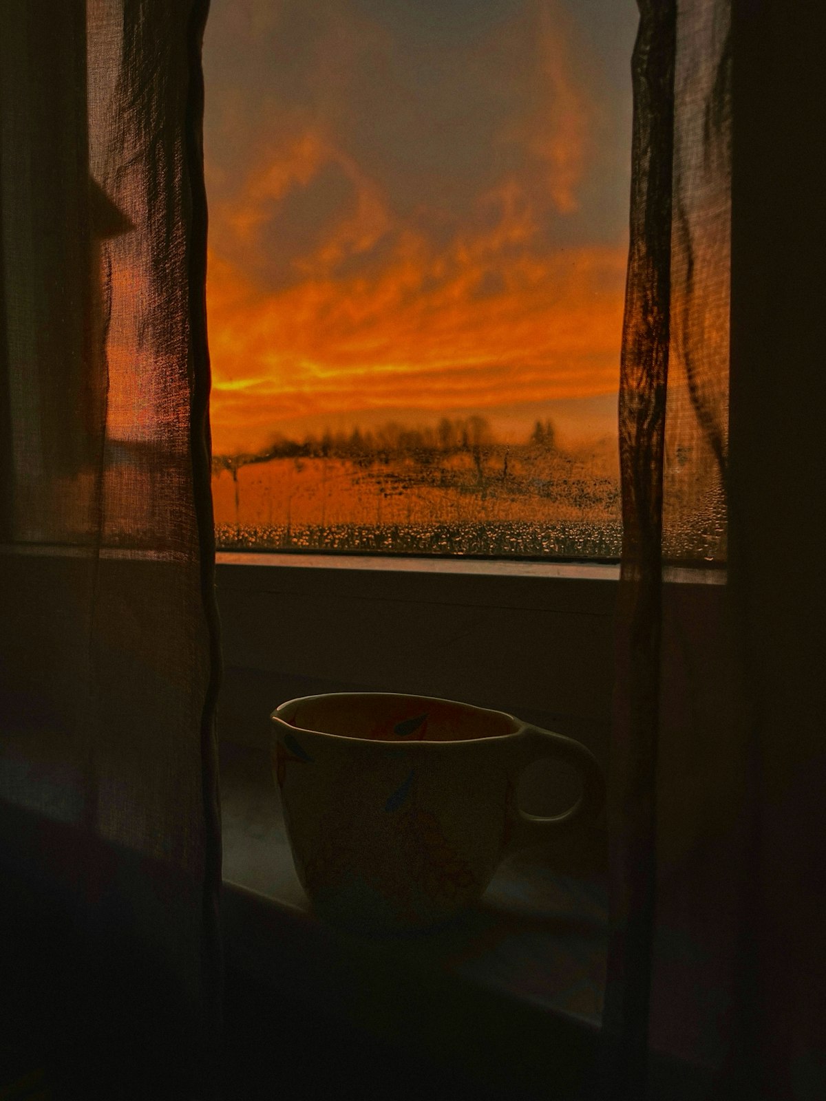 窓際のコーヒーと朝焼けの光