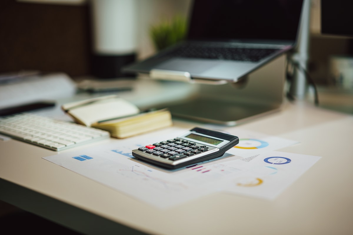 A calculator sitting next to a laptop